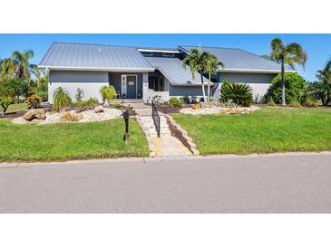 Gray house with metal roof, landscaping, and paved pathway at 120 Lookout Point Dr, Osprey, FL 34229
