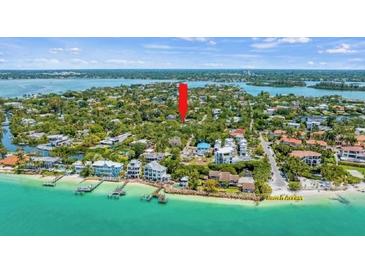 Aerial view of waterfront property with beach access, lush landscaping, and nearby homes at 157 Garden Ln, Sarasota, FL 34242