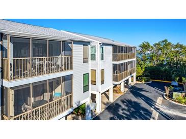 Two-story building with screened balconies overlooking a parking area at 3601 E Bay Dr # 203, Holmes Beach, FL 34217