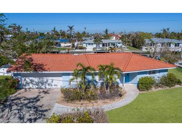 Cute light blue house with a red tile roof, driveway, and nicely landscaped lawn at 621 Emerald Ln, Holmes Beach, FL 34217