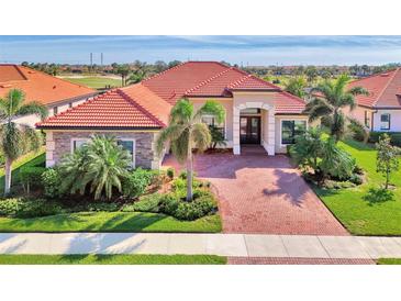 Luxury home with brick driveway, lush landscaping, and a tile roof at 25261 Spartina Dr, Venice, FL 34293