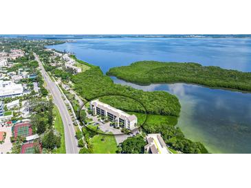 Aerial view of waterfront condo building with lush landscaping and tennis courts at 4540 Gulf Of Mexico Dr # 304, Longboat Key, FL 34228