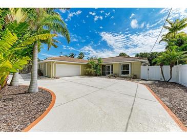 Tan single story house with a three car garage and circular driveway under a bright blue sky at 505 72Nd St, Holmes Beach, FL 34217