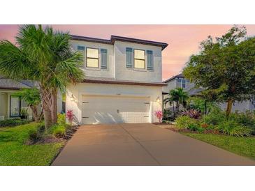 Charming two-story home showcasing a well-manicured lawn, lush landscaping, and a spacious two-car garage at 5548 Summit Gln, Bradenton, FL 34203