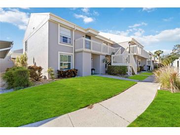 Exterior view of a light gray condo building with green lawn and walkway at 5956 7Th W Ave, Bradenton, FL 34209