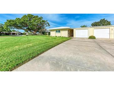 House exterior featuring a spacious lawn, attached garage, and attractive landscaping at 3430 Village Green Dr # 623, Sarasota, FL 34239