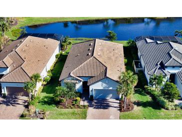 Aerial view of three homes with tile roofs, landscaping, and a lake at 4711 Arpino Ct, Lakewood Ranch, FL 34211