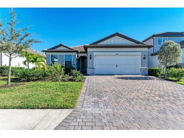 One-story home with gray siding, white garage door, and a paved driveway at 6043 Bluestar Ct, Bradenton, FL 34211