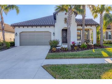 White one-story house with brown roof, landscaping, and a two-car garage at 249 Palmaria Ct, Nokomis, FL 34275