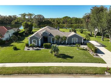 Single-Gathering home with lake view, landscaped yard, and driveway at 8755 Misty Creek Dr, Sarasota, FL 34241