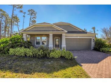 Gray house with stone accents, landscaping, and a brick driveway at 2179 W Price Blvd, North Port, FL 34286