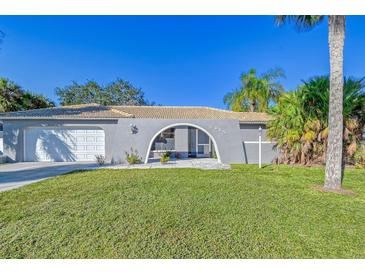 House exterior featuring a gray color scheme, arched entryway, and well-manicured lawn at 3615 Kingston Blvd, Sarasota, FL 34238