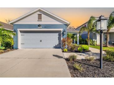 Two-car garage, light-blue exterior, landscaped front yard, and walkway at 3632 Shimmering Oaks Dr, Parrish, FL 34219