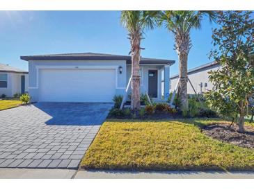 Single-story home with gray exterior, paver driveway, and landscaping at 148 Whiteland Bnd, Nokomis, FL 34275
