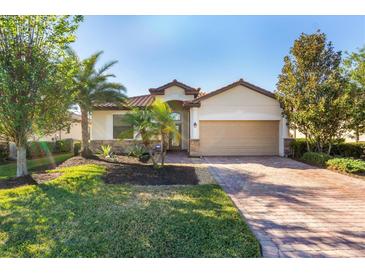 Single-story home with a tan exterior, brown roof, and landscaped lawn at 6870 Willowshire Way, Bradenton, FL 34212