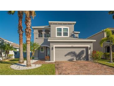 Two-story house with gray siding, brick driveway, and palm trees at 8430 Nandina Dr, Sarasota, FL 34240