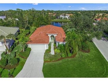 Aerial view of single-story house with red tile roof, landscaped yard, and lake nearby at 1109 Scherer Way, Osprey, FL 34229