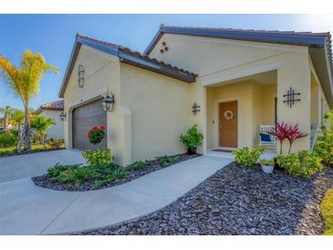 Tan house with brown garage door, walkway, landscaping, and a wreath on the front door at 364 Palmaria Ct, Nokomis, FL 34275