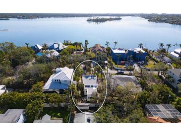 An aerial shot showcasing a house near the water, surrounded by other homes and greenery at 4189 Roberts Point Cir, Sarasota, FL 34242