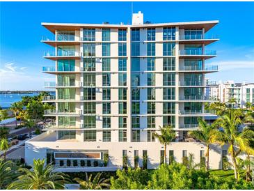 Modern condo building featuring floor-to-ceiling windows and private balconies overlooking lush tropical landscaping at 111 Golden Gate Pt # 403, Sarasota, FL 34236