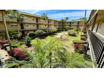 Lush courtyard with tropical landscaping, seating area, and a two-story building at 11485 Oakhurst Rd # 200-220, Largo, FL 33774