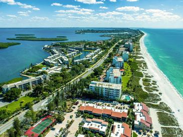 Aerial view of coastal community, showcasing beachfront property, pools, and lush landscaping at 4440 Exeter Dr # 104, Longboat Key, FL 34228