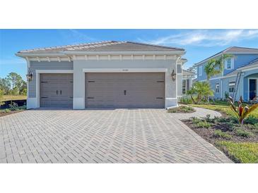 Two-car garage, light gray exterior, paved driveway, landscaping at 10142 Crystal Isles Cir, Sarasota, FL 34241