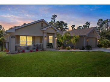 Charming single-story home boasts a well-manicured lawn and lush landscaping, with an attached garage and inviting front porch at 4989 Ageman Ave, North Port, FL 34288