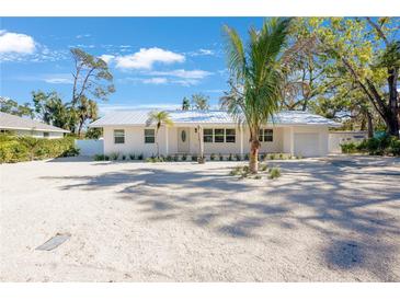 White single-story home with metal roof, landscaping, and large driveway at 1205 29Th W St, Bradenton, FL 34205