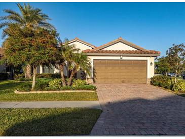 Single-story home with brown garage door and brick driveway, landscaping, and palm trees at 20680 Vita Ct, Venice, FL 34293