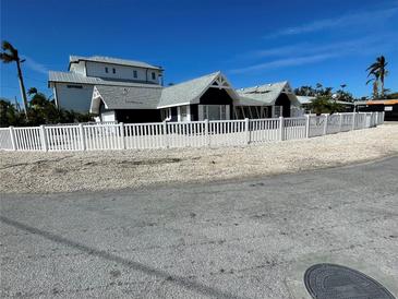 Newly renovated home with a white picket fence and tropical landscaping at 237 S Harbor Dr, Holmes Beach, FL 34217