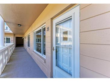 Condo entrance featuring a well-lit exterior hallway, door with glass, and an adjacent window at 2435 Sumatran Way # 35, Clearwater, FL 33763