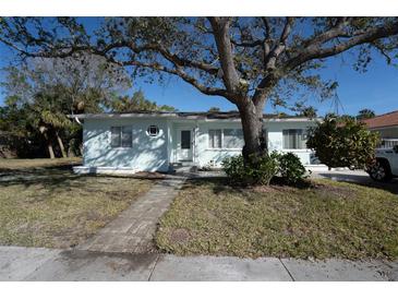 Charming light blue beach house with a paved walkway and large tree at 745 Bruce Ave, Clearwater Beach, FL 33767