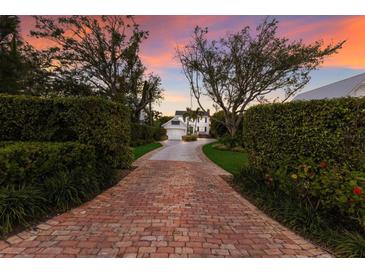 Long brick driveway leading to a charming two-story home with mature trees and manicured landscaping at 4110 Riverview Blvd, Bradenton, FL 34209