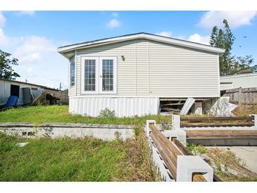 Tan mobile home with overgrown yard and partial view of a fenced area at 5829 Coventry Dr, Tampa, FL 33615