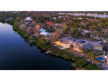 Aerial view of a waterfront home with a dock and pool at sunset at 7618 Midnight Pass Rd, Sarasota, FL 34242