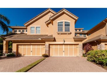 Tan two-story townhome with two-car garage and brick paver driveway at 8280 Villa Grande Ct, Sarasota, FL 34243