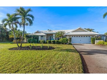 Charming one-story home with a white tiled roof, landscaped yard, and palm trees at 348 Red Ash Cir, Englewood, FL 34223