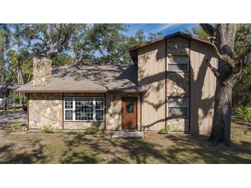 Two-story house with stone and wood siding, a brown door, and large windows at 6919 64Th E Ave, Palmetto, FL 34221