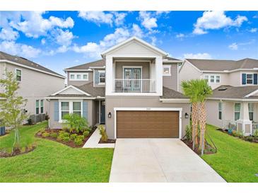 Two-story home with attached garage, balcony, manicured lawn, and beautiful landscaping at 33443 Landsman Loop, Wesley Chapel, FL 33543