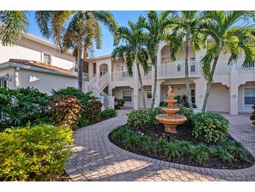 Exterior of a two-story condo building with lush landscaping and a fountain at 4264 Central Sarasota Pkwy # 111, Sarasota, FL 34238