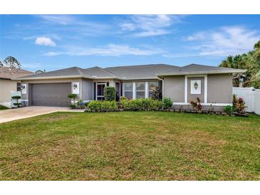 Charming single-story home with a well-manicured lawn and colorful landscaping enhancing curb appeal at 6261 Keating Ave, North Port, FL 34291