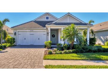 Single-story home with a white front door, two-car garage, and landscaped lawn at 8089 Sandstar Way, Sarasota, FL 34240