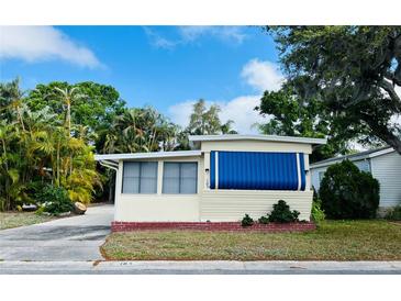Charming single-story home featuring cream siding, a red brick foundation and a large blue awning for shade at 103 Oakwood Blvd, Sarasota, FL 34237