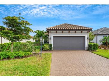 House exterior featuring a gray garage door, landscaping, and a brick driveway at 4727 Motta Ct, Bradenton, FL 34211