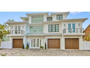 Striking three-story coastal home featuring a symmetrical design, three-car garage, and charming Juliette balconies at 329 Tarpon St, Anna Maria, FL 34216