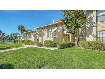 Exterior view of condo building with lush landscaping and a well-maintained lawn at 4410 Weybridge # 91, Sarasota, FL 34235