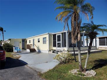Single-wide yellow manufactured home with a screened porch and palm trees at 5414 Burma Ct, Bradenton, FL 34207