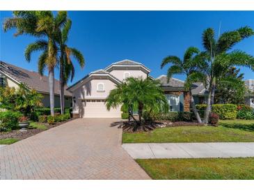Attractive home with paver driveway, lush landscaping, and palm trees at 7223 Orchid Island Pl, Bradenton, FL 34202