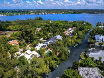 Stunning aerial view of waterfront homes surrounded by lush greenery and a beautiful blue bay at 1214 Sea Plume Way, Sarasota, FL 34242